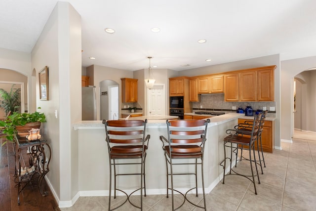 20111 Hilltop Ranch Dr, Montgomery, TX 77316 - kitchen with a peninsula, tasteful backsplash, black appliances, recessed lighting, and arched walkways