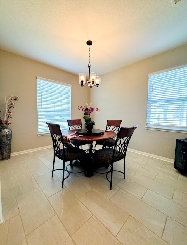 dining space with a chandelier, baseboards, and light tile patterned floors