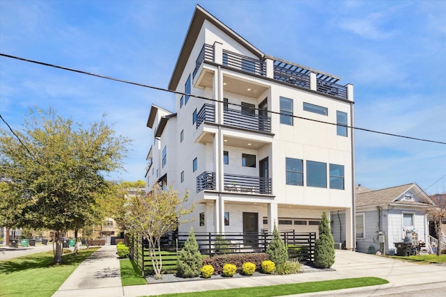 view of front facade with driveway, an attached garage, stucco siding, and a balcony