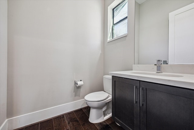 bathroom featuring toilet, baseboards, vanity, and wood finished floors