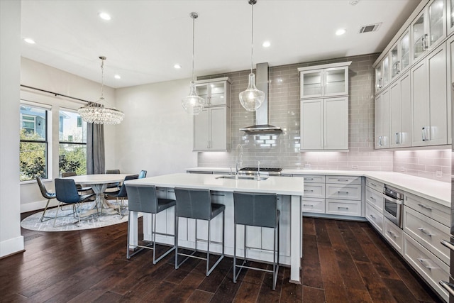 kitchen with dark wood-style flooring, a sink, wall chimney exhaust hood, light countertops, and oven