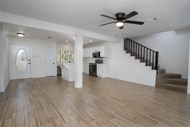 entrance foyer with light wood-style flooring, baseboards, ceiling fan, visible vents, and stairway