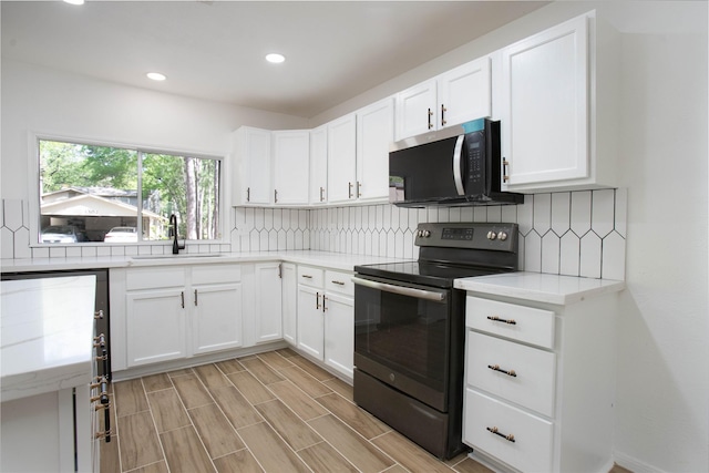 kitchen with backsplash, stainless steel microwave, black range with electric stovetop, and a sink