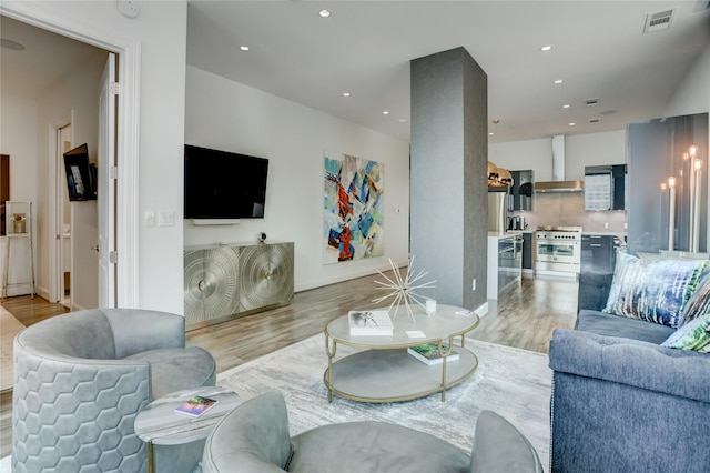 living room featuring visible vents, light wood-style flooring, baseboards, and recessed lighting