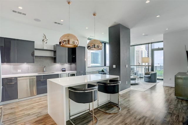 kitchen featuring dishwasher, light wood finished floors, modern cabinets, a sink, and light countertops