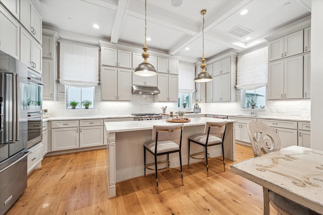 823 Blackshire Ln, Houston, TX 77055 - kitchen with under cabinet range hood, a breakfast bar area, a healthy amount of sunlight, and backsplash