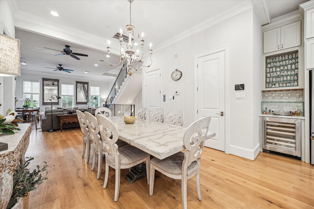 dining area with wine cooler, stairs, light wood-style floors, and crown molding