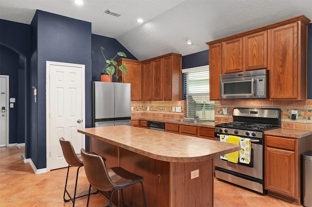 4407 Iron Creek Ct, Fresno, TX 77545 - kitchen with stainless steel appliances, a sink, lofted ceiling, a kitchen island, and decorative backsplash