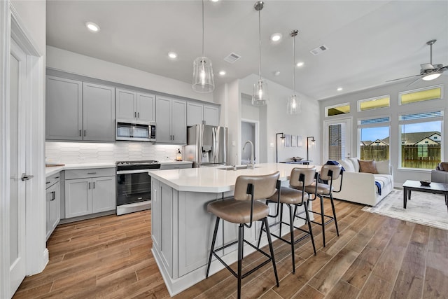 kitchen featuring gray cabinetry, visible vents, open floor plan, light countertops, and appliances with stainless steel finishes