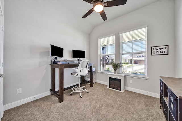 carpeted office space with vaulted ceiling, baseboards, a ceiling fan, and a glass covered fireplace