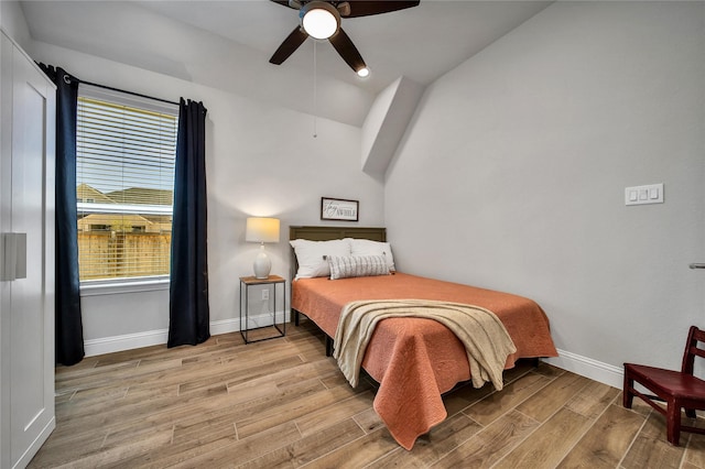 bedroom with baseboards, wood finished floors, lofted ceiling, and ceiling fan