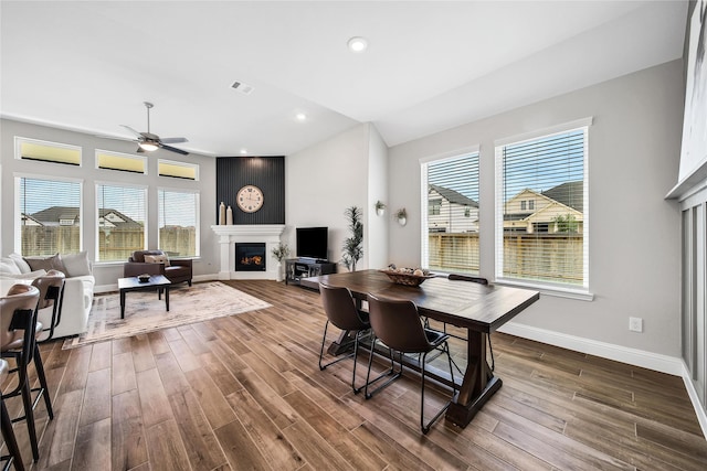 dining area featuring plenty of natural light, dark wood-type flooring, baseboards, and a glass covered fireplace