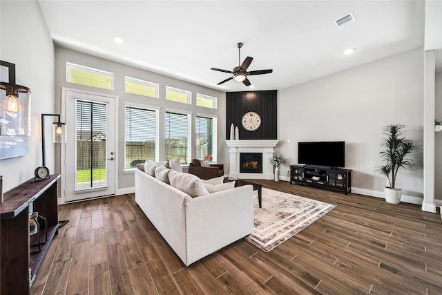 living room featuring visible vents, recessed lighting, ceiling fan, a large fireplace, and dark wood-style floors