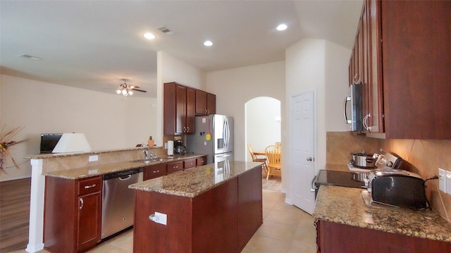 15407 Vincennes Oak St, Cypress, TX 77429 - kitchen with a sink, a peninsula, arched walkways, a kitchen island, and appliances with stainless steel finishes