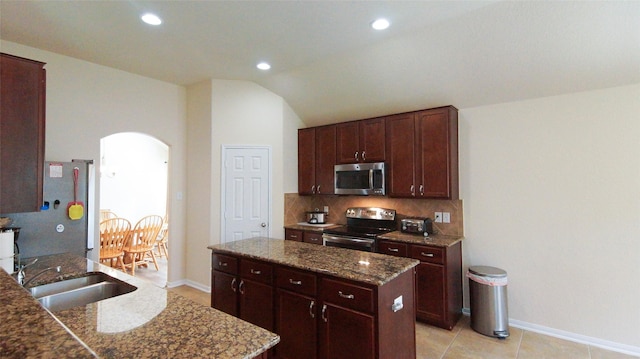 15407 Vincennes Oak St, Cypress, TX 77429 - kitchen with a sink, stainless steel appliances, dark stone countertops, arched walkways, and a kitchen island