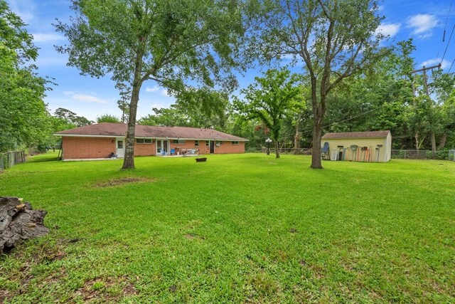 view of yard featuring a storage unit, fence, and an outbuilding