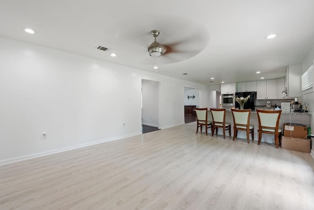 living room with light wood-style flooring, a ceiling fan, visible vents, baseboards, and recessed lighting