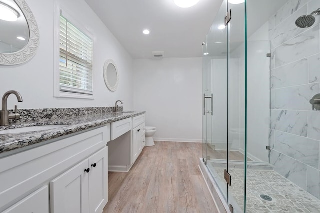 full bathroom with double vanity, wood finished floors, a stall shower, and a sink