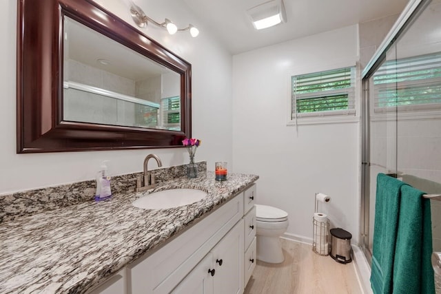 full bath with toilet, wood finished floors, a stall shower, baseboards, and vanity