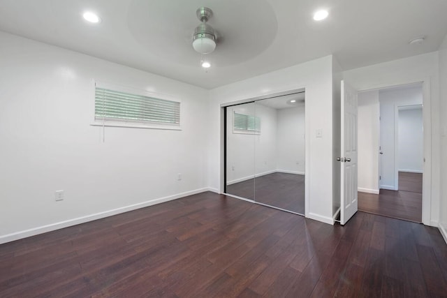 unfurnished bedroom with a closet, recessed lighting, baseboards, ceiling fan, and dark wood-type flooring