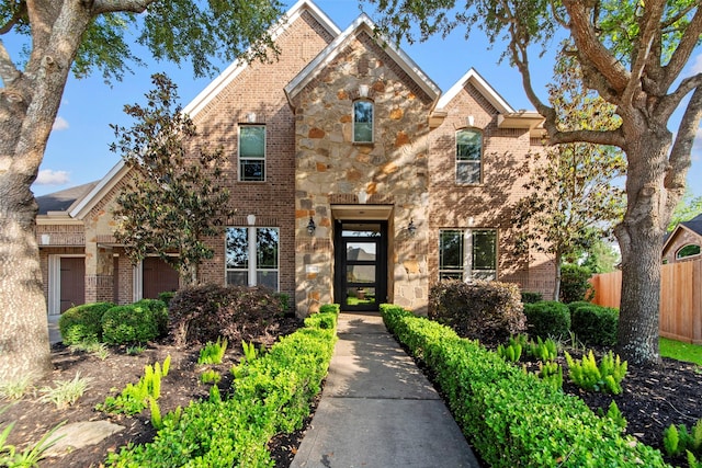 view of front of house featuring stone siding, fence, and brick siding
