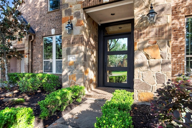 view of exterior entry with stone siding and brick siding