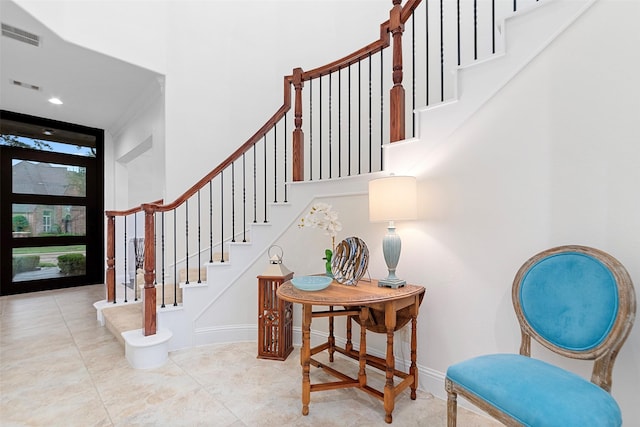 tiled entryway with ornamental molding, stairs, baseboards, and visible vents