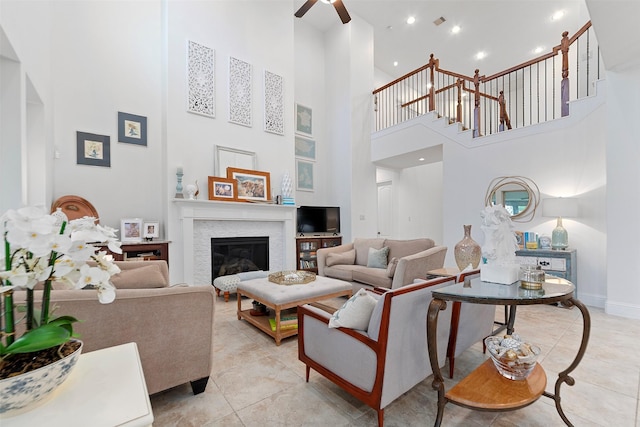 living room with light tile patterned floors, a high ceiling, visible vents, ceiling fan, and a glass covered fireplace