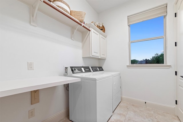 clothes washing area featuring baseboards, washer and dryer, and cabinet space
