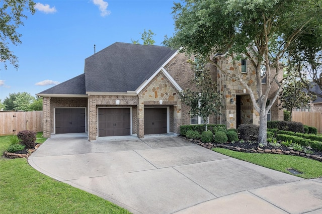 view of front of property with a garage, fence, concrete driveway, brick siding, and roof with shingles