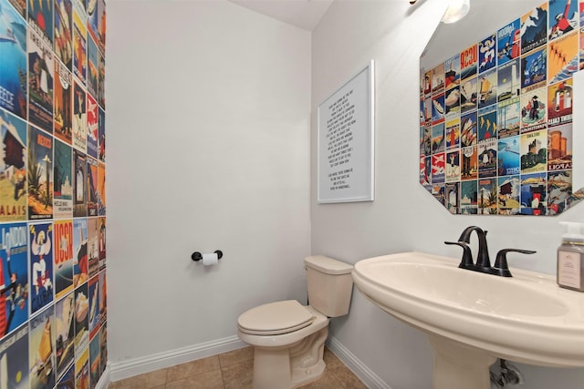 bathroom featuring toilet, baseboards, tile patterned floors, and a sink