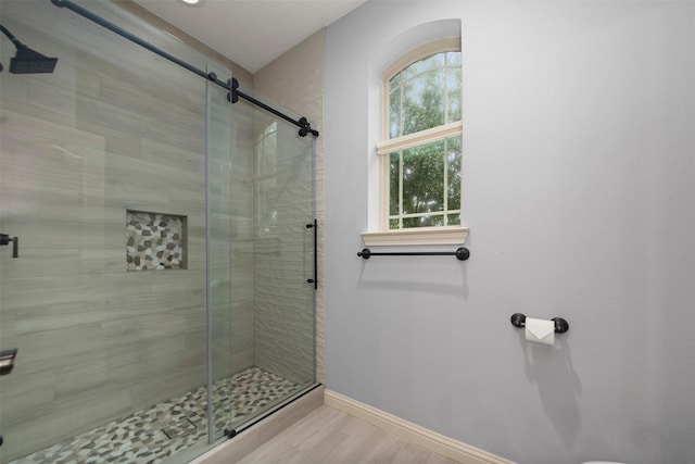 full bathroom with a stall shower, baseboards, and wood finished floors