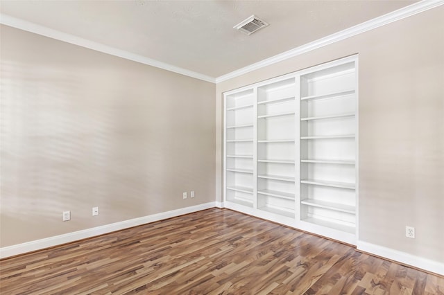 unfurnished room featuring baseboards, wood finished floors, visible vents, and built in shelves