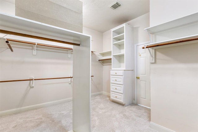 walk in closet with visible vents and light colored carpet