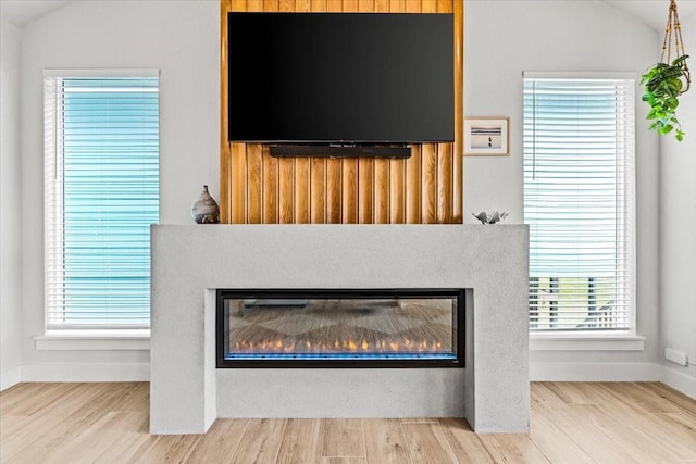 interior details with wood finished floors, baseboards, and a glass covered fireplace