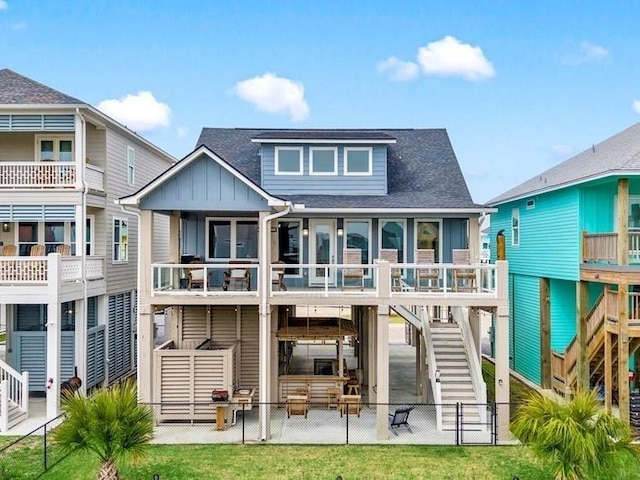 back of house featuring board and batten siding, fence, a patio, stairs, and a shingled roof