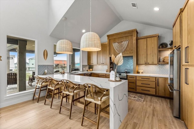 kitchen featuring freestanding refrigerator, lofted ceiling, a breakfast bar, visible vents, and light wood-type flooring