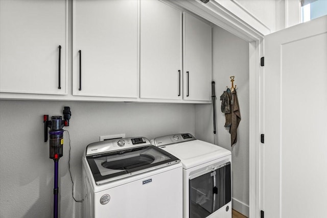 clothes washing area featuring cabinet space and washing machine and clothes dryer