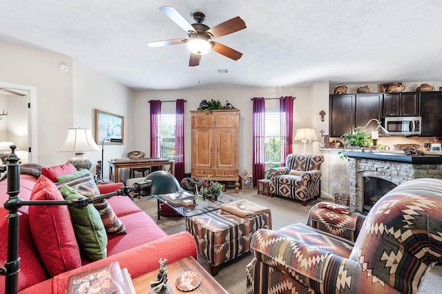 living room with light colored carpet, a healthy amount of sunlight, ceiling fan, and a textured ceiling