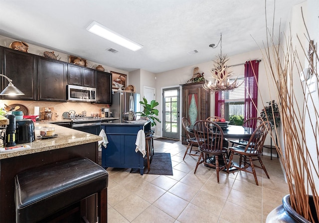 kitchen featuring decorative backsplash, dark brown cabinetry, visible vents, appliances with stainless steel finishes, and a chandelier