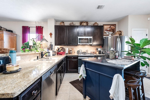 kitchen with light tile patterned flooring, stainless steel appliances, visible vents, and a sink