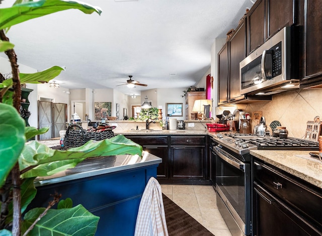 kitchen featuring a peninsula, stainless steel appliances, tasteful backsplash, ceiling fan, and light tile patterned floors