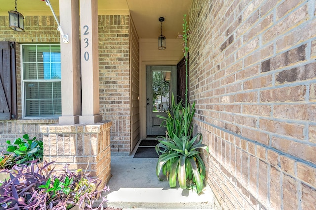 doorway to property with covered porch and brick siding