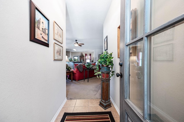 corridor featuring light colored carpet, light tile patterned floors, and baseboards