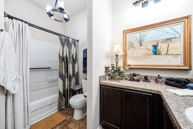 bathroom featuring toilet, stone finish flooring, vanity, and a chandelier