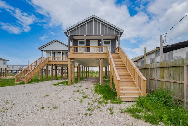 rear view of house featuring covered porch, stairs, dirt driveway, and a carport