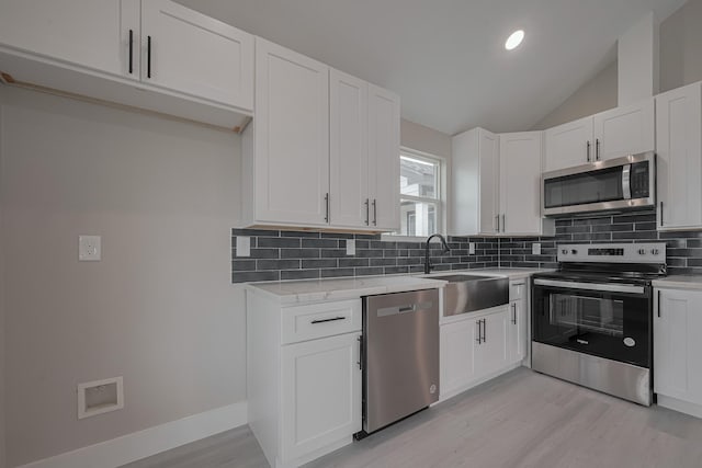 kitchen with light wood-style flooring, a sink, backsplash, stainless steel appliances, and white cabinets