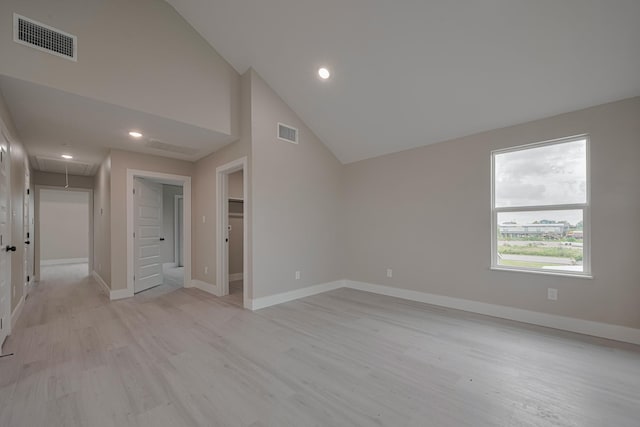 unfurnished bedroom featuring light wood-style floors, attic access, visible vents, and a walk in closet
