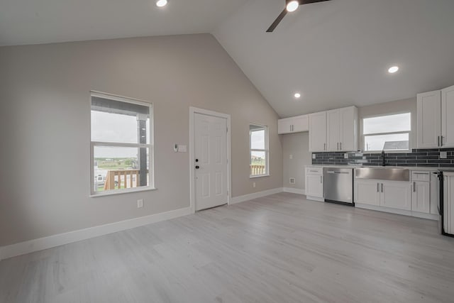 kitchen featuring a ceiling fan, dishwasher, a sink, high vaulted ceiling, and white cabinets