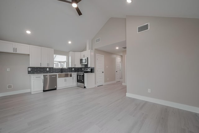 kitchen with appliances with stainless steel finishes, visible vents, open floor plan, and a sink
